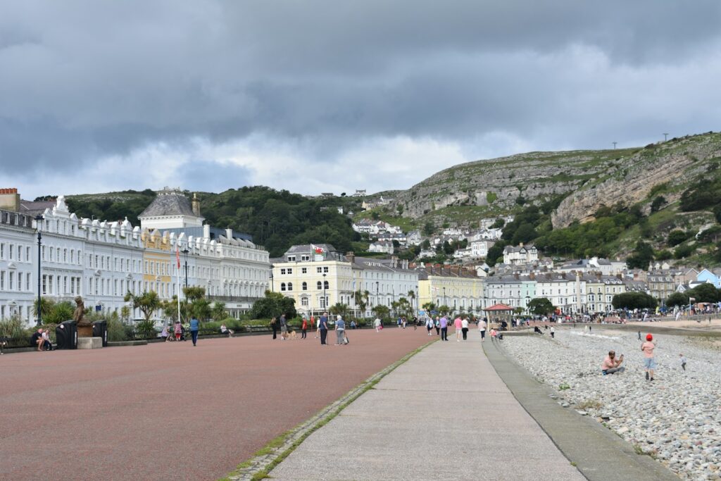 People walking along a street beside a hill in Llandudno, the North Wales seaside resort